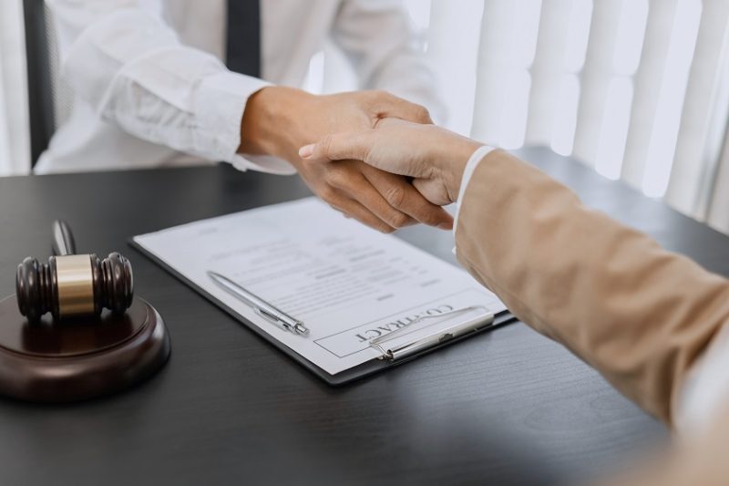 Lawyer consultant shaking hand with client in law firm.